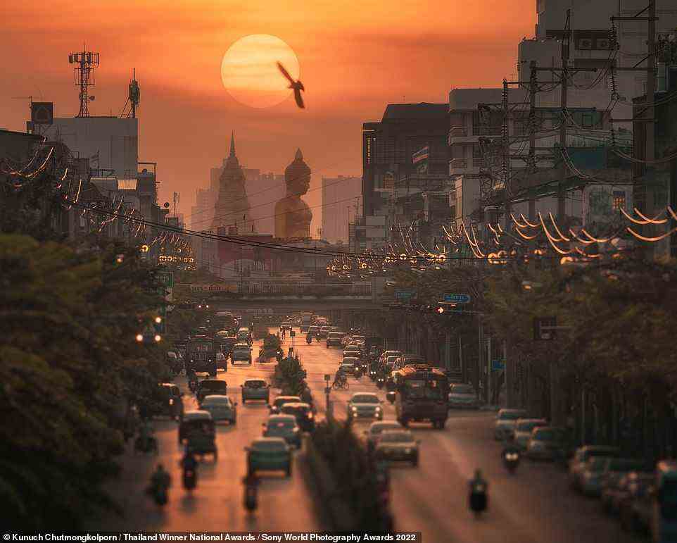 The top prize in the national award for Thailand went to photographer Kunuch Chutmongkolporn, for this beautiful image taken in Bangkok last October. In the background, the Buddha statue from the city's Wat Paknam Bhasicharoen temple can be seen. Chutmongkolporn says: 'Around the fourth week of October, the sun sets behind the statue. To get a high-impact shot, I used a super-telephoto zoom lens to compress the sun with a bird, the statue, and the city in the foreground'