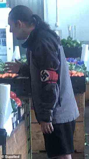 Im Bild ein Mann, der auf einem Markt in Melbourne eine Nazi-Hakenkreuz-Armbinde trägt