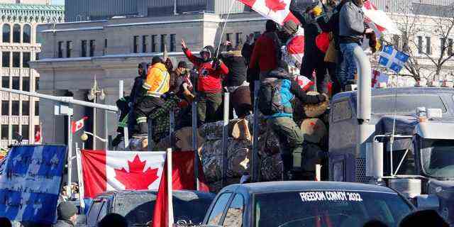Demonstranten stehen auf einem Anhänger mit Baumstämmen, während Trucker und Unterstützer an einem Konvoi teilnehmen, um gegen COVID-19-Impfstoffmandate für grenzüberschreitende Lkw-Fahrer in Ottawa, Ontario, Kanada, am 29. Januar 2022 zu protestieren. (REUTERS/Patrick Doyle/File Photo )