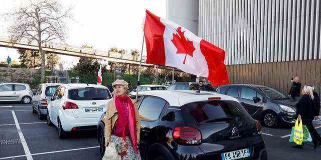 Eine Frau und ihr Hund stehen vor dem Start neben einer kanadischen Flagge "Convoi de la liberte" (The Freedom Convoy), ein Fahrzeugkonvoi-Protest, der am 9. Februar 2022 in Nizza, Frankreich, in Nizza, Frankreich, zusammenläuft, um gegen den Impfstoff und die Beschränkungen der Coronavirus-Krankheit (COVID-19) zu protestieren. 