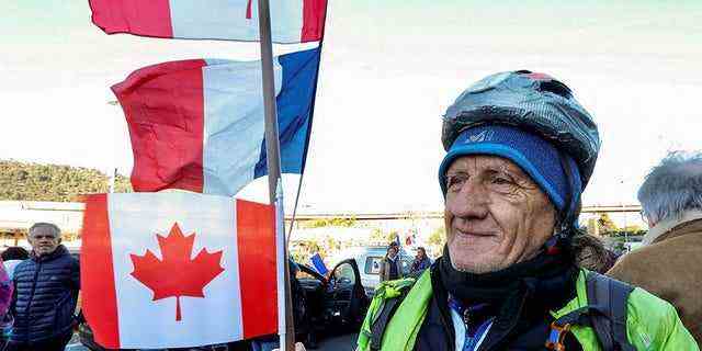 Ein französischer Aktivist hält vor dem Start eine kanadische Flagge "Convoi de la liberte" (The Freedom Convoy), ein Fahrzeugkonvoi-Protest, der am 9. Februar 2022 in Nizza, Frankreich, auf Paris zuläuft, um gegen den Coronavirus-Impfstoff und die Beschränkungen zu protestieren. 