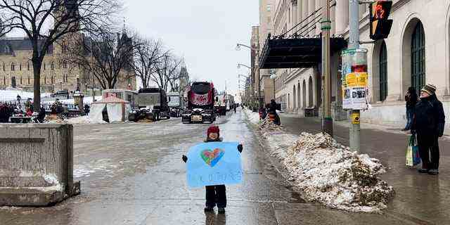 Ein Junge hält a "Danke Trucker" unterschreiben, während er durch die Lkw-Schlange in Ottawa geht