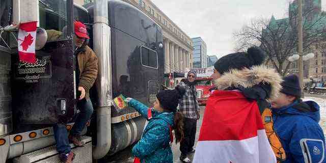 Ein Mädchen und ihre Familie gehen durch die Reihe der Trucker und verteilen Dankeskarten