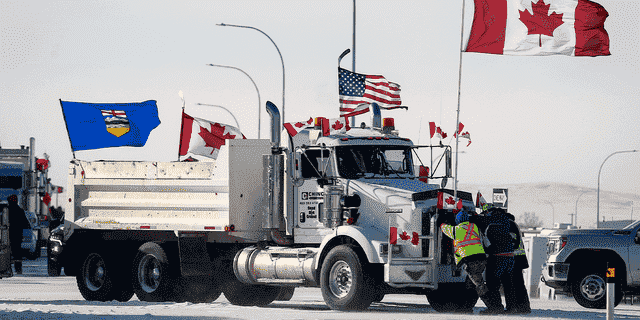 Fahrer arbeiten daran, einen Kieslaster zu bewegen, nachdem ein Durchbruch die Sackgasse gelöst hat, in der Demonstranten gegen das Impfmandat gegen COVID-19 am Mittwoch, dem 2. Februar 2022, die Autobahn am belebten US-Grenzübergang in Coutts, Alberta, blockierten. 
