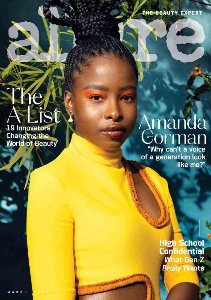 Amanda Gorman on the cover of Allure Magazine’s March 2022 issue. She wears a yellow turtleneck with cutout details, neon orange eye makeup, a glossy lip, and simple drop earrings. Her hair is braided and piled on top of her head in a bun. 