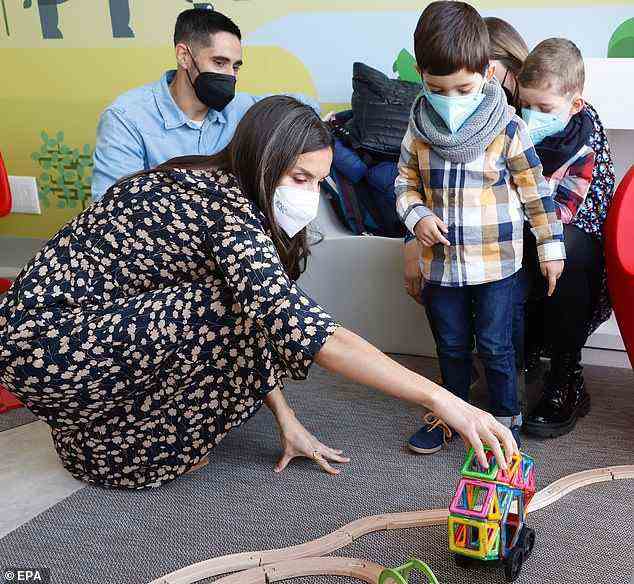 The Spanish monarch is seen playing with a group of children at the hospital during her visit today