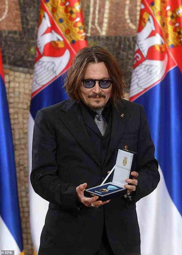The actor wore his dark brown locks down and parted as he displayed the medal he received