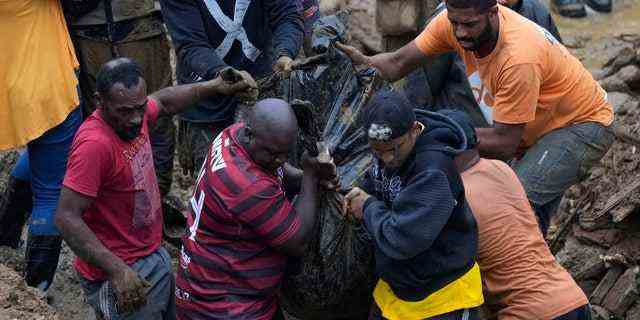 Anwohner und Freiwillige entfernen am Mittwoch, 16. Februar 2022, die Leiche eines Schlammlawinenopfers in Petropolis, Brasilien. 