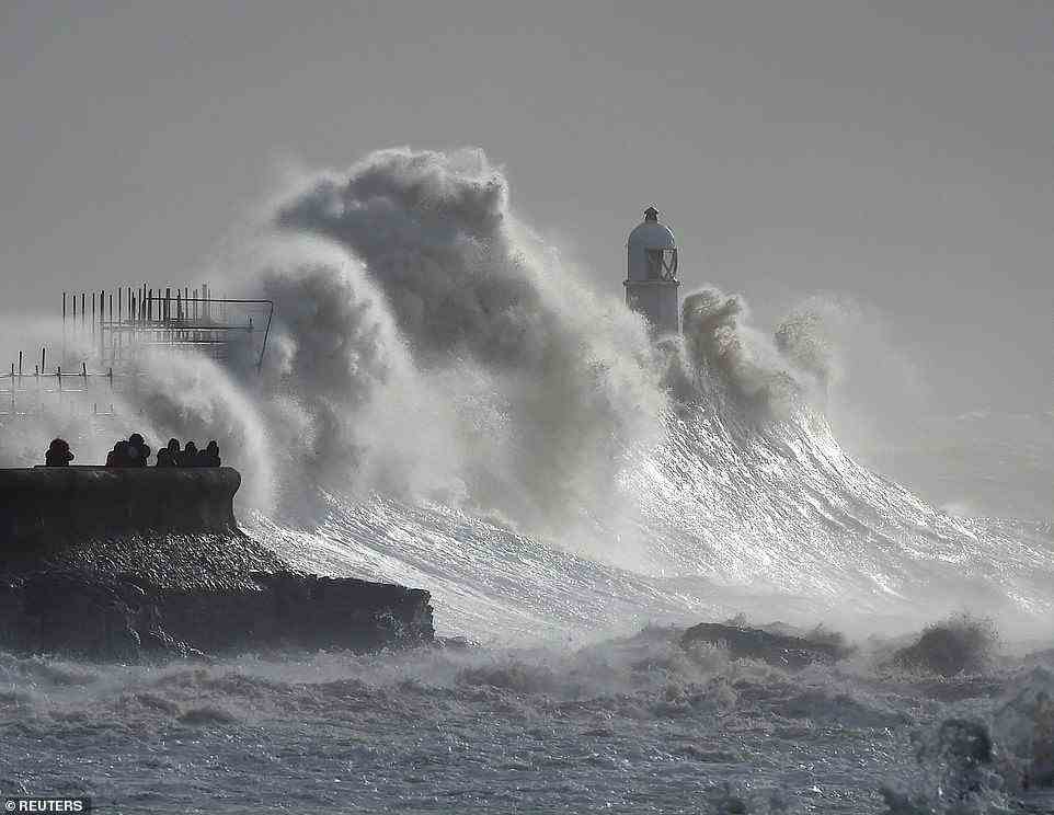 Waves crash against a lighthouse during Storm Franklin this morning at Porthcawl in Bridgend, South Wales