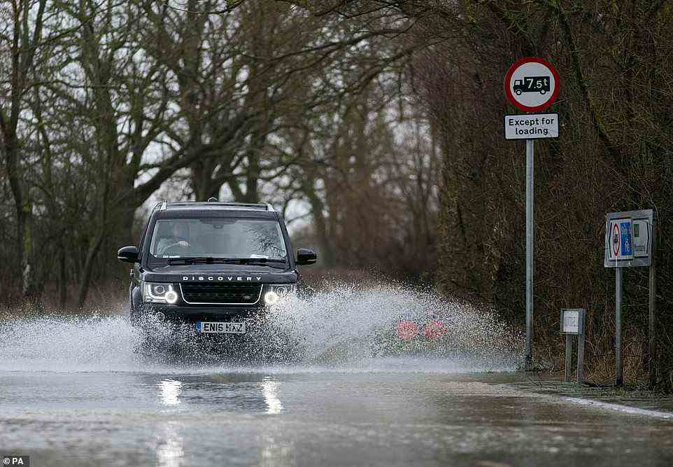 A car travels along a flooded road in Mountsorrel in Leicestershire today as Britons were warned to brace for high winds