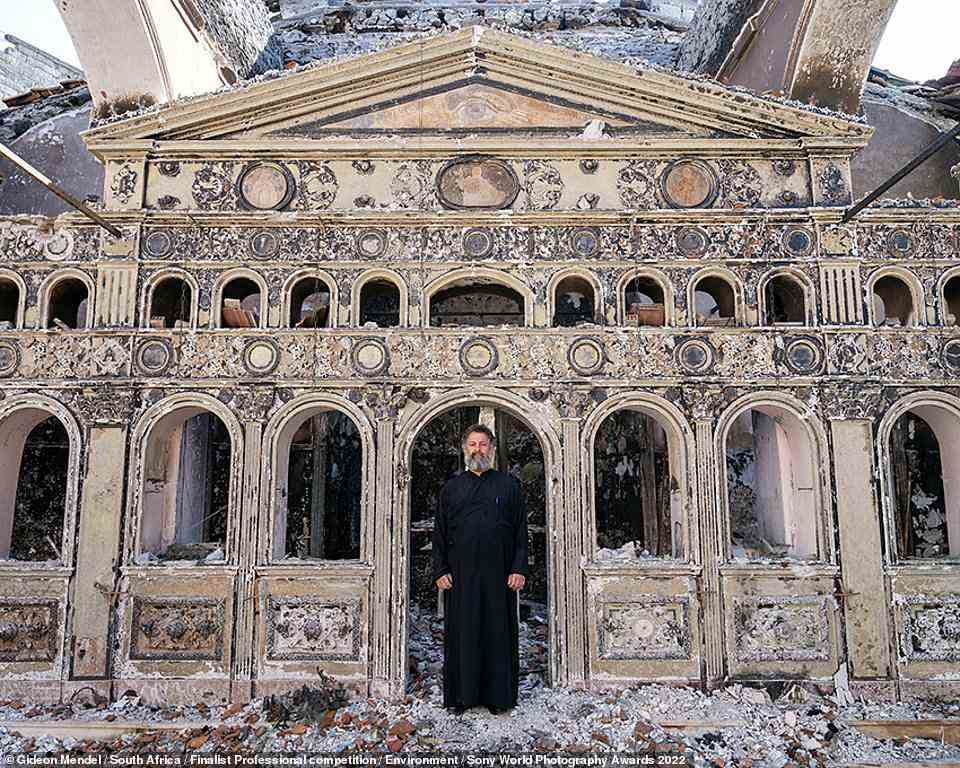 This is another shot by Mendel. In this image, Father Ioannis Siaflekis stands in the doorway of the derelict 18th-century Agion Taxiarchon Church in Kokinomilia Village on the Greek Island of Evia. The church was a victim of the fires that devastated the island during an unprecedented heatwave in the summer of 2021