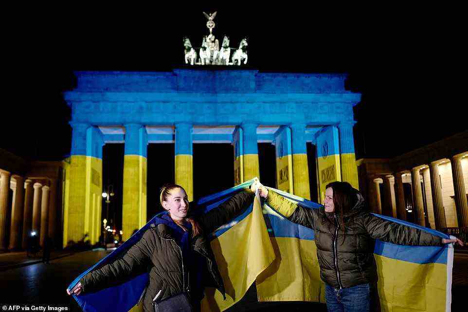 Berlin Mayor Franziska Giffey said in a statement: 'We are showing our solidarity with the people of Ukraine, the many Berliners with Ukrainian roots but also with the many Russians who want peace in Russia and Ukraine'. Above: Two women hold Ukrainian flags aloft in front of the Brandenburg Gate