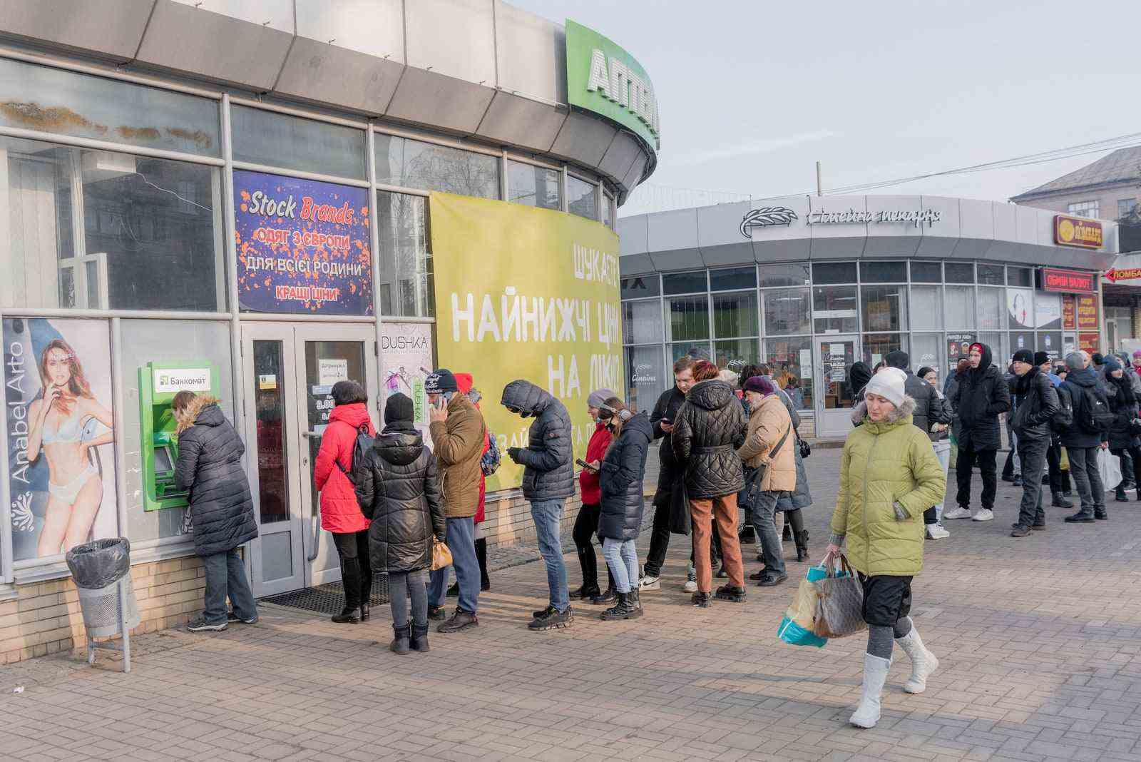 Während die russische Invasion in der Ukraine voranschreitet, warten Menschen in Slowjansk Schlange, um Geld an Geldautomaten zu bekommen.
