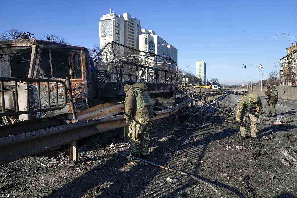 Ukrainian soldiers investigate debris of a burning military truck on a street in Kyiv, Ukraine on Saturday