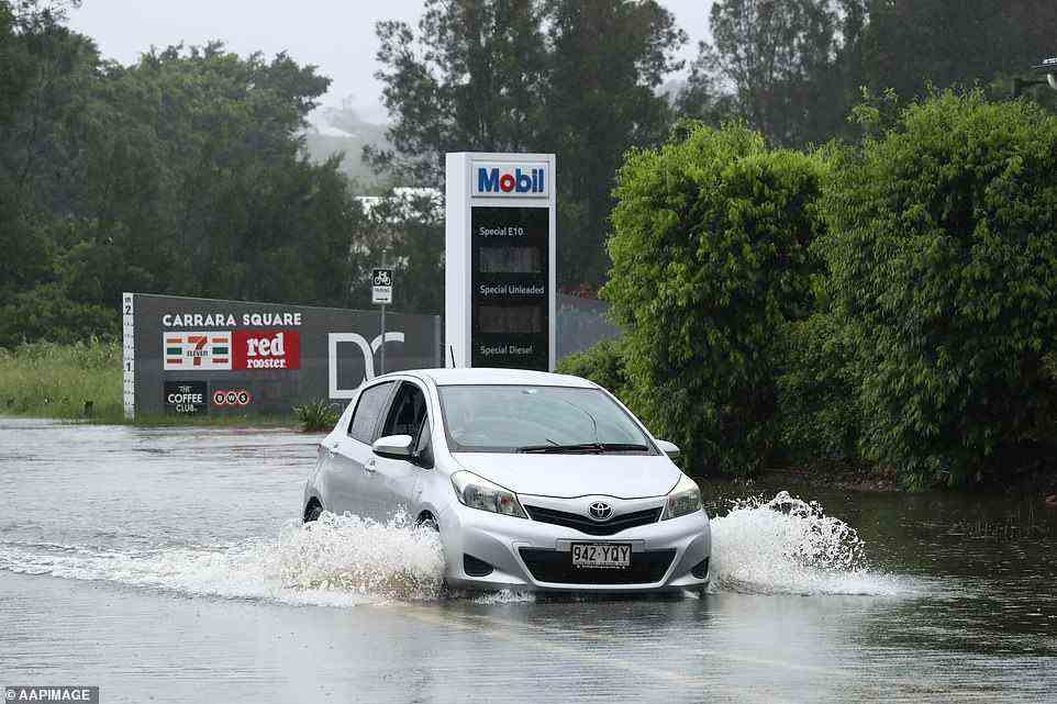 A car attempts to drive through Carara despite rising floodwaters in the Gold Coast and large parts of south-east Queensland