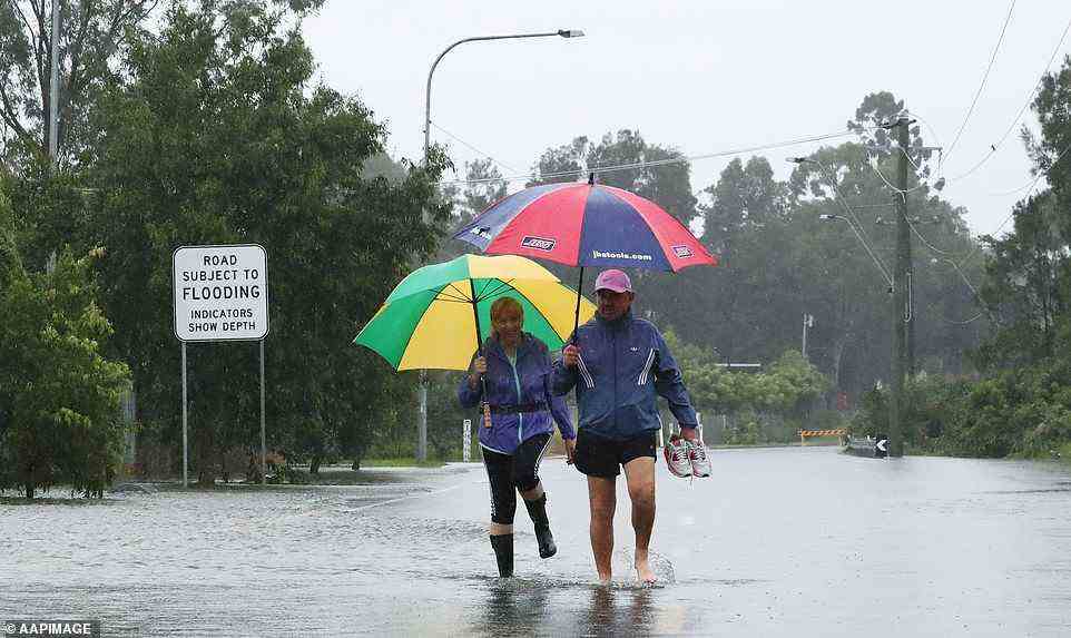 Gold Coast residents walk through rising floodwaters in Carrara on Sunday morning