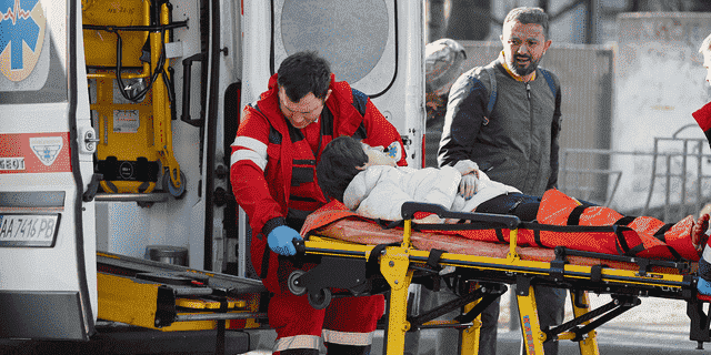 Am 26. Februar 2022 transportieren medizinische Spezialisten eine Frau – die beim Beschuss eines Wohnhauses verwundet wurde – zu einem Krankenwagen, während ihr Ehemann in der Nähe in Kiew, Ukraine, steht.