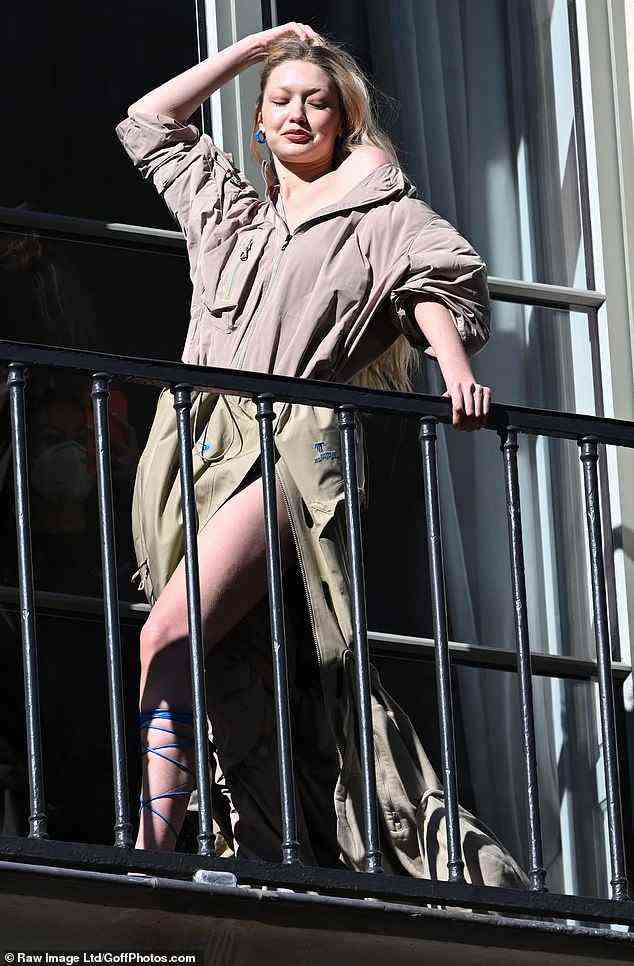 Gigi Hadid zeigte mit gebleichten blonden Augenbrauen eine auffällige Darstellung, als sie ihre Beine in einem Kamelmantel während eines Balkon-Fotoshootings inmitten von Paris F zeigte