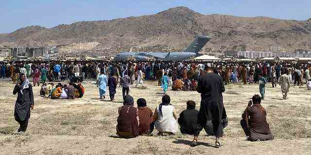 Hunderte von Menschen versammeln sich im August 2021 in der Nähe eines C-17-Transportflugzeugs der US Air Force an einem Perimeter des internationalen Flughafens in Kabul, Afghanistan. 