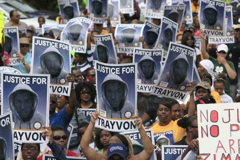 Demonstranten halten Schilder mit einem Foto eines Jungen, der einen Hoodie trägt, und den Worten "Gerechtigkeit für Trayvon"