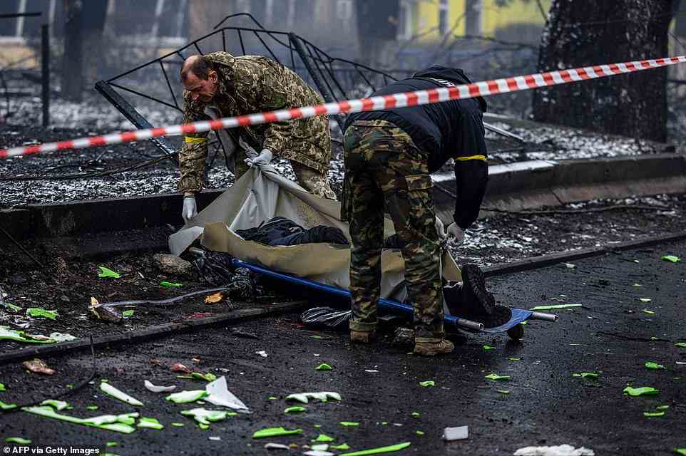 Police officers remove the body of a passerby killed in Tuesday's airstrike that hit Kyiv's main television tower