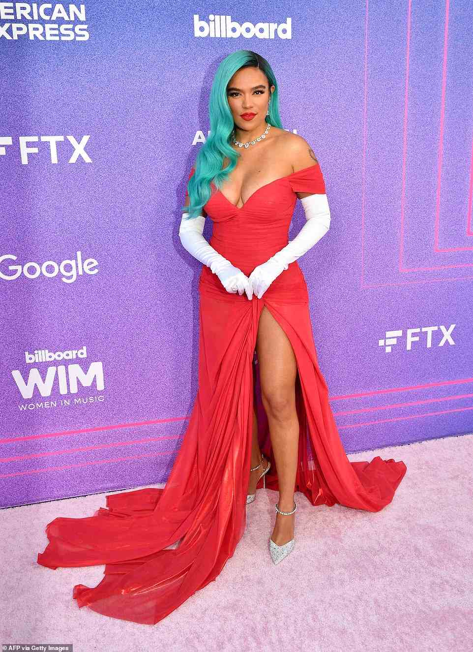 Belle of the ball: Karol G looked like the belle of the ball as she posed in a bright red off-the-shoulder gown with a dramatic slit up one leg