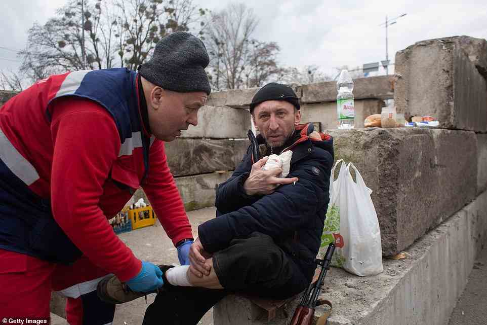 Ruslan from the Territorial Defense shows where a bullet came through his jacket as he gets medical help for a wound received during shelling near Irpin earlier today