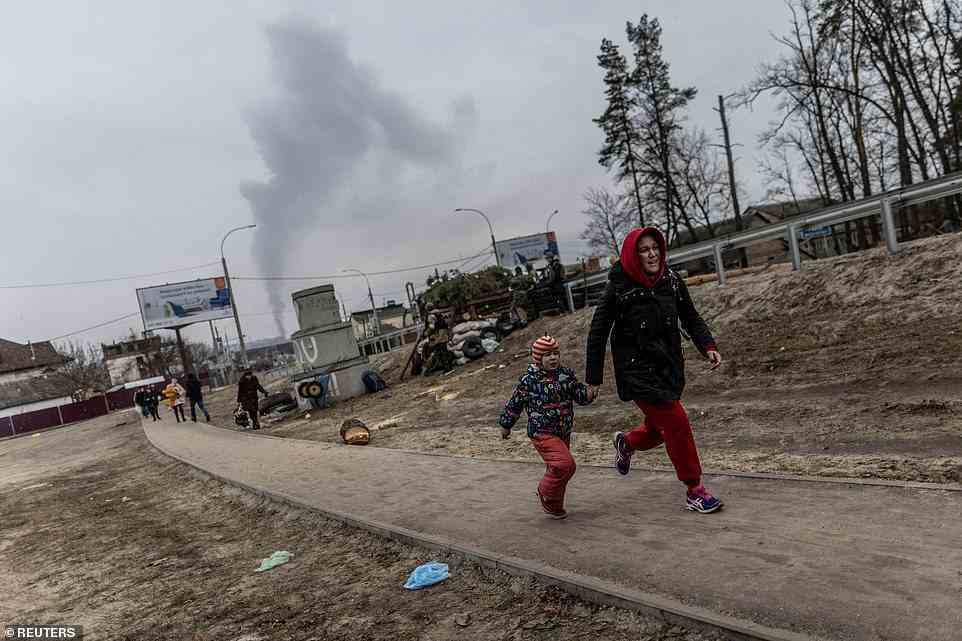 Local residents run for cover as they escape from the town of Irpin, after heavy shelling from Russian troops