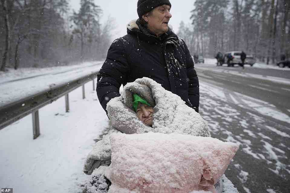 A wheelchair-bound woman is covered in snow as she is evacuated from Irpin while temperatures plunge