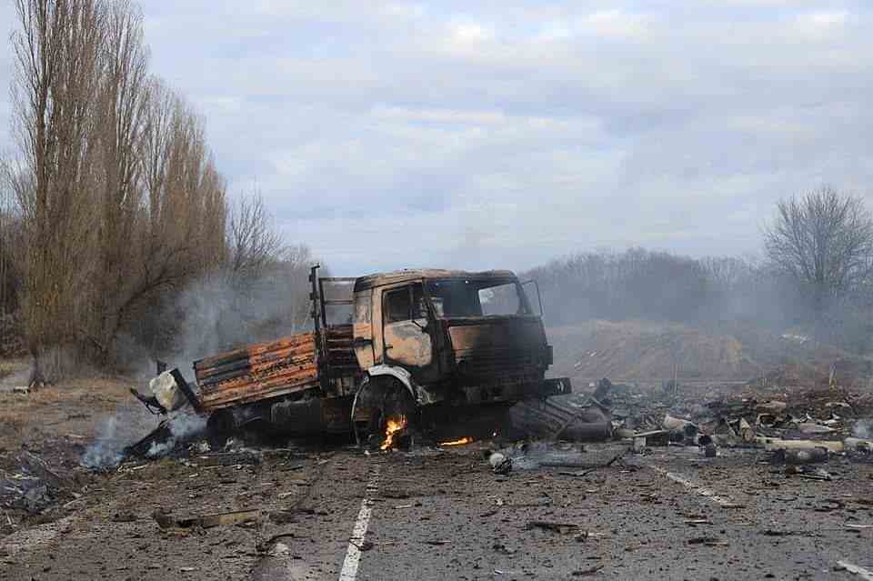 A burned-out supply truck is seen amidst the ruins of other vehicles on a road in Ukraine