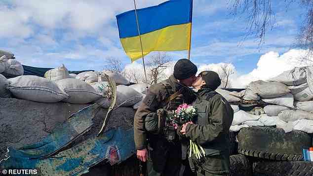 Mitglieder der Nationalgarde der Ukraine, Oleksandr und Olena, küssen sich am Dienstag bei ihrer Hochzeit an einem Kontrollpunkt an einem unbekannten Ort
