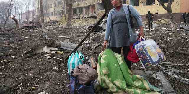 Eine Frau geht am Mittwoch, dem 9. März 2022, vor das durch Beschuss beschädigte Entbindungsheim in Mariupol, Ukraine. 