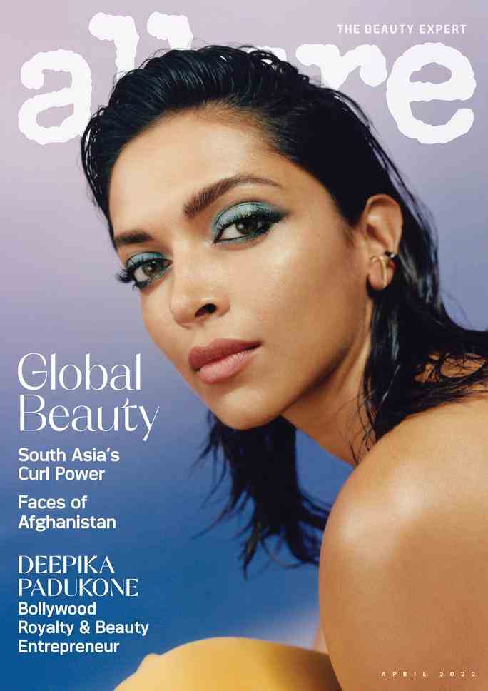 Bollywood actor Deepika Padukone on the cover of Allure magazine in front of a blue ombre background. In a close-up portrait, Padukone is wearing bright blue eye shadow and matte pink lipstick. Her wet hair is slicked back, and she looks over her bare shoulder into the camera. 