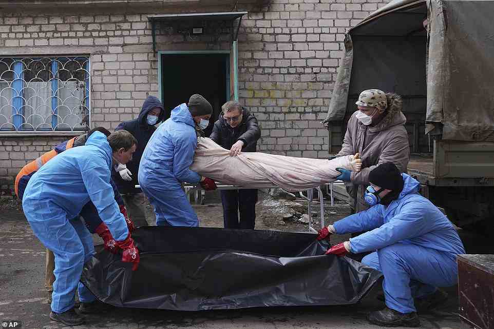Mortuary workers move a dead body into a plastic bag in the outskirts of Mariupol, March 9, 2022