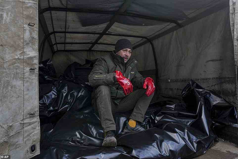 A mortuary worker sits on body bags before they were transported to the outskirts of Mariupol, March 9, 2022