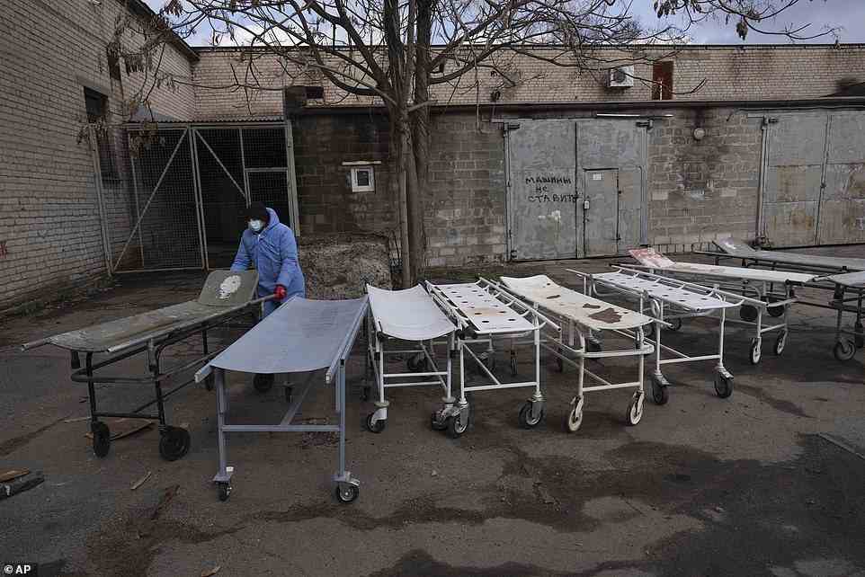 A mortuary worker wheels a stretcher used to move dead bodies before they are buried on the outskirts of Mariupol
