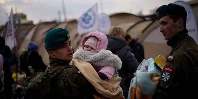 Ein polnischer Soldat hält ein Baby, als Flüchtlinge, die vor dem Krieg in der benachbarten Ukraine fliehen, am Donnerstag, 10. März 2022, an der polnischen Medyka-Grenze ankommen. 