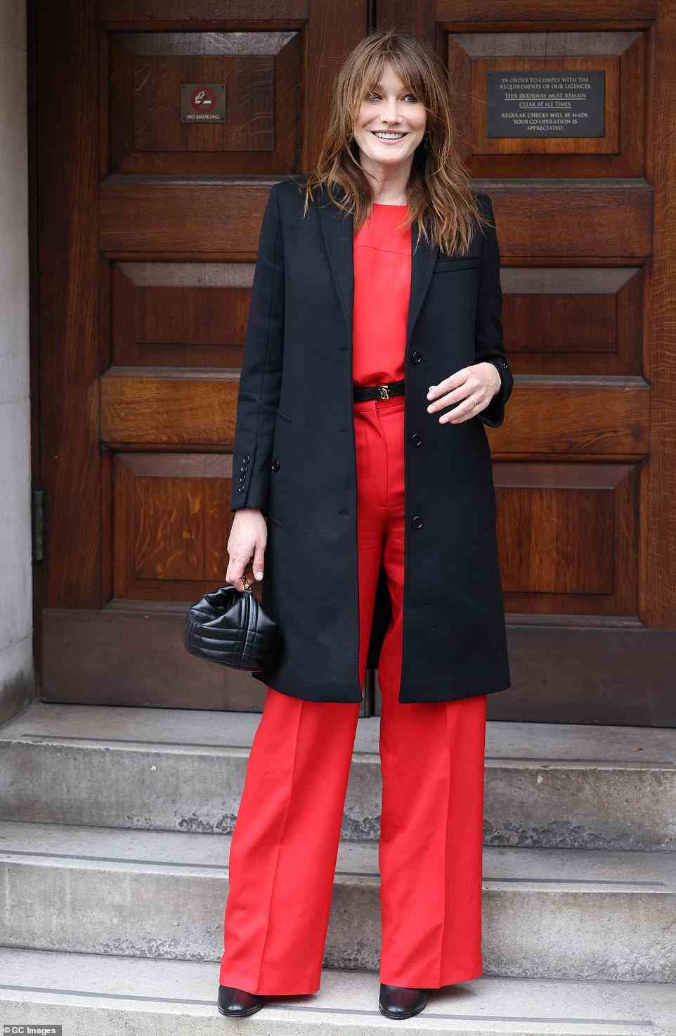 Chic: Carla completed her look with a matching red top, thin-strapped Burberry belt and plunging black pea coat