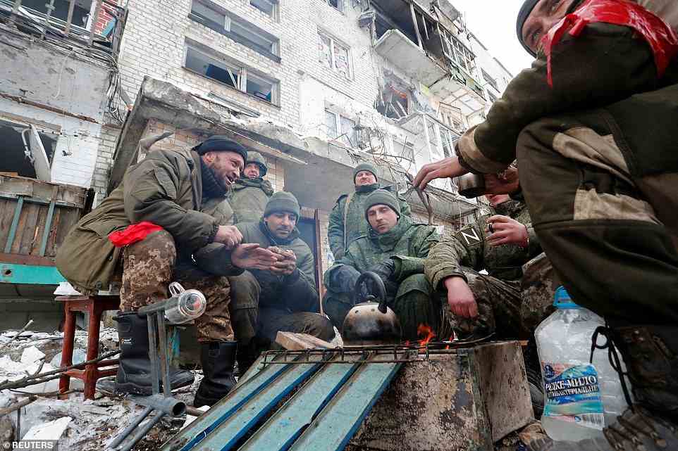 Service members of pro-Russian troops in uniforms without insignia gather around a fire outside a residential building in Volnovakha in the pro-separatist Donetsk region