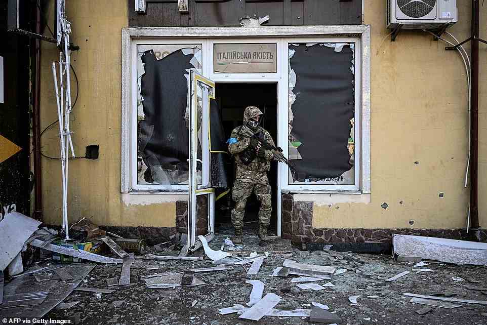 A Ukrainian serviceman exits a damaged building after shelling in Kyiv with Russians closing in on the city