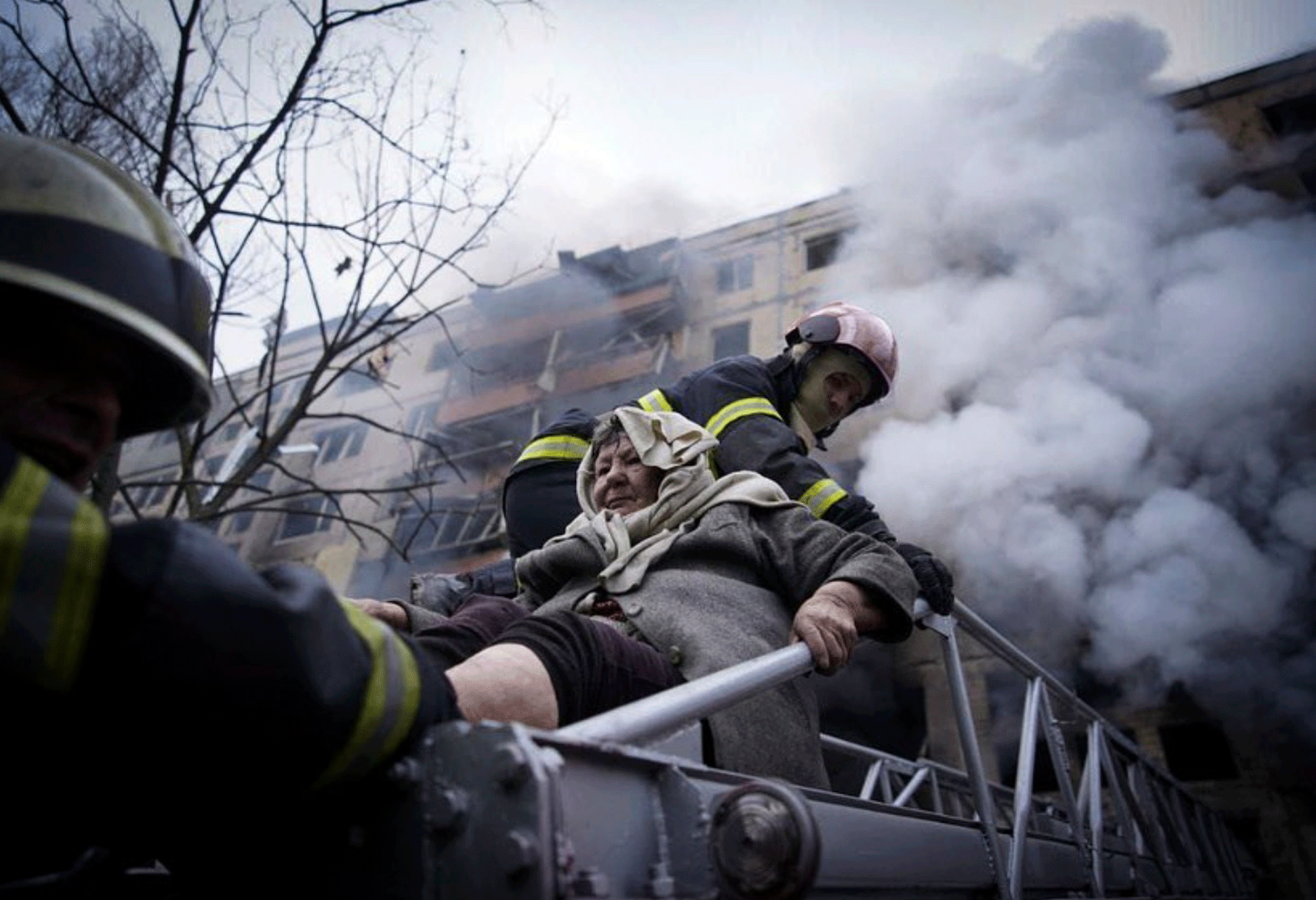 Auf diesem Foto, das vom Pressedienst des ukrainischen staatlichen Notdienstes veröffentlicht wurde, evakuieren Feuerwehrleute eine ältere Frau aus einem Wohnhaus, das am Montag, dem 14. März 2022, in Kiew, Ukraine, von Granaten getroffen wurde. 