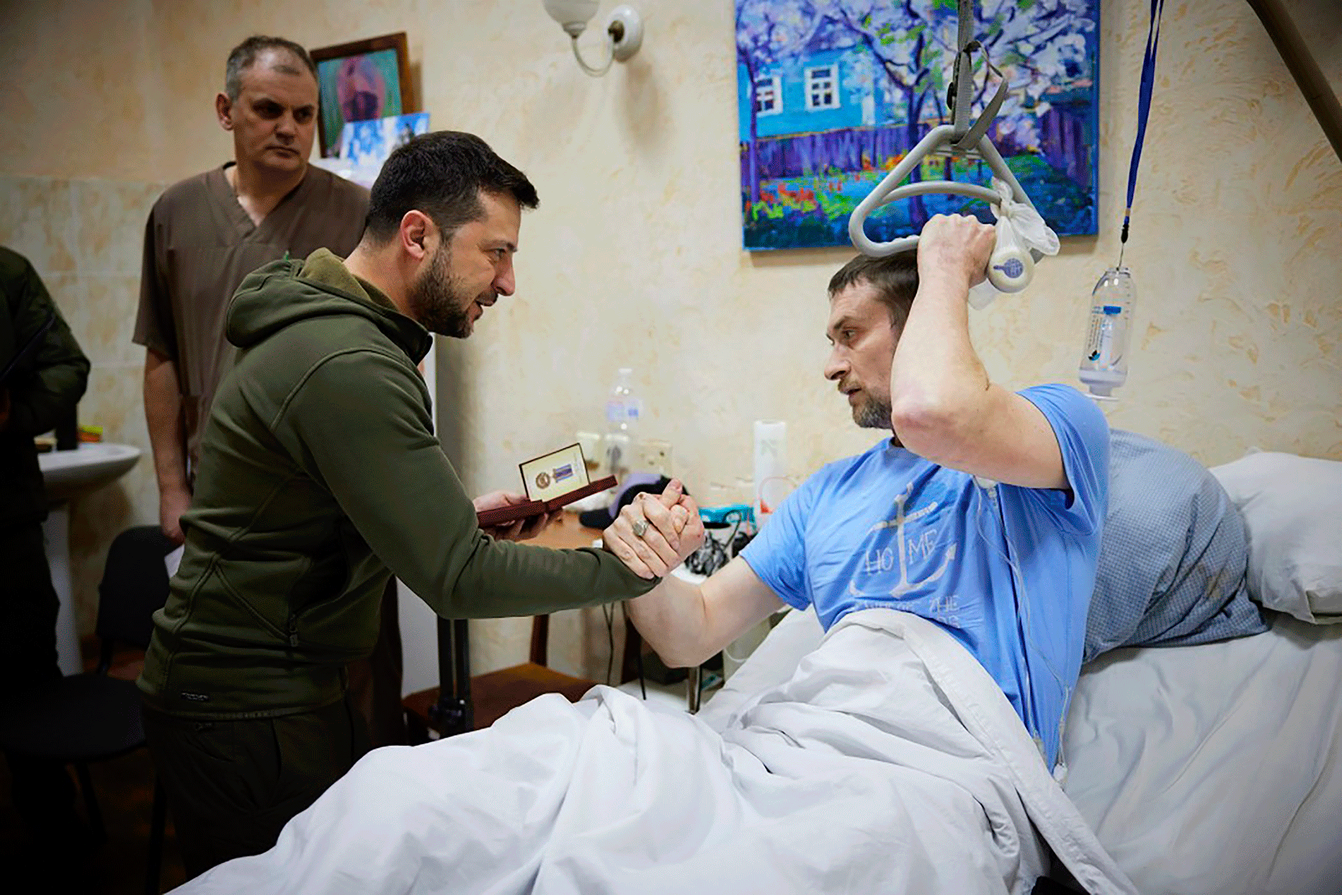 Auf diesem Foto, das am Sonntag, dem 13. März 2022 vom Presseamt ​​des ukrainischen Präsidenten zur Verfügung gestellt wurde, schüttelt Präsident Wolodymyr Selenskyj, Mitte, einem verwundeten Soldaten bei seinem Besuch in einem Krankenhaus in Kiew, Ukraine, die Hand. 