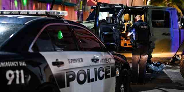 Ein Polizeibeamter aus Miami Beach inspiziert am 22. März 2021 das Innere eines Autos auf dem Ocean Drive in Miami Beach, Florida.