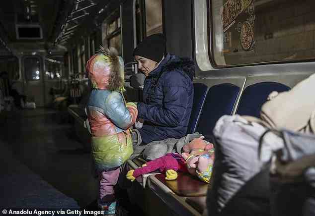 Pictured: A woman speaks to a child on a train in a subway tunnel where they have sheltered in Kyiv