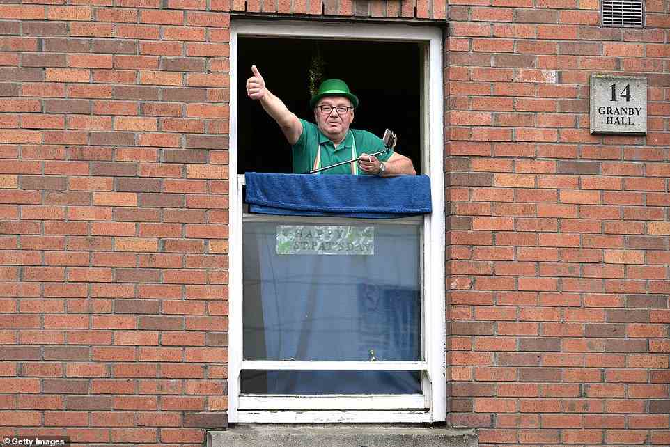 A Dublin man dressed in green gives a thumbs up from a window during the St Patrick's Day parade today
