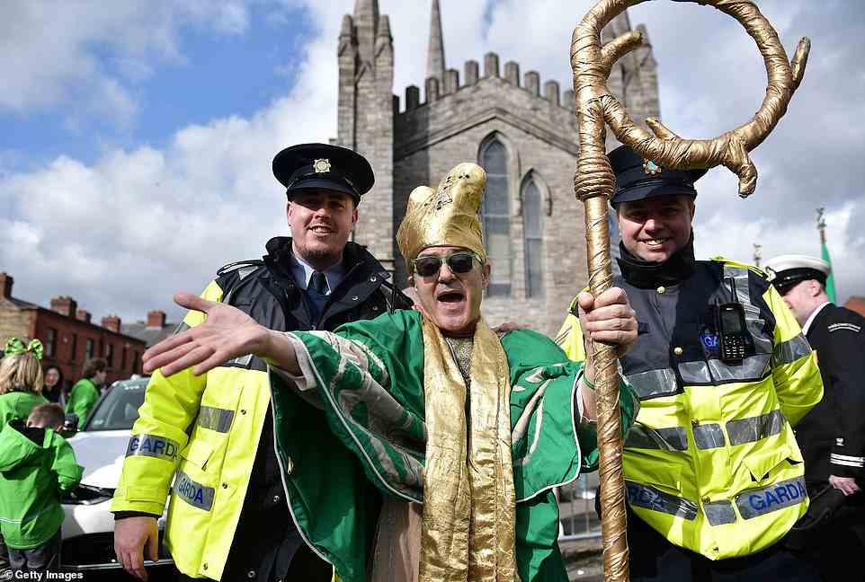 A man in fancy dress poses with police for a photo as Dublin locals celebrate St Patrick's Day today