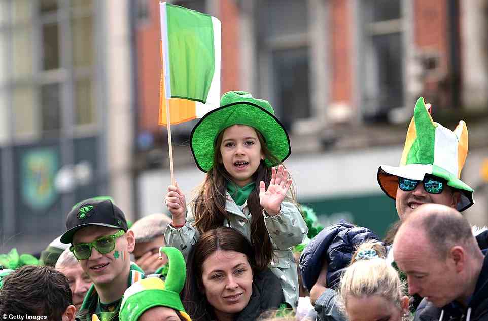 A young girl waved as she sat on a family member's shoulders while watching the St Patrick's Day parade in Dublin today