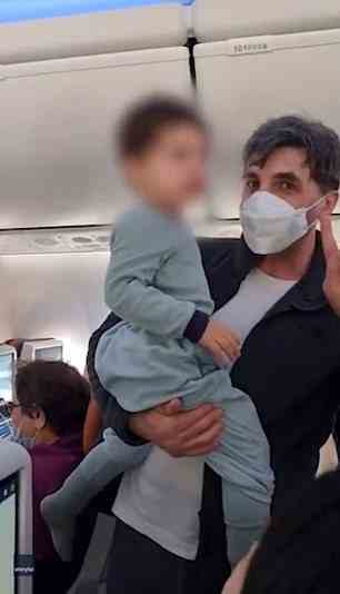 Das verärgerte Kind ist in den Armen eines Mannes auf dem Flug zu sehen