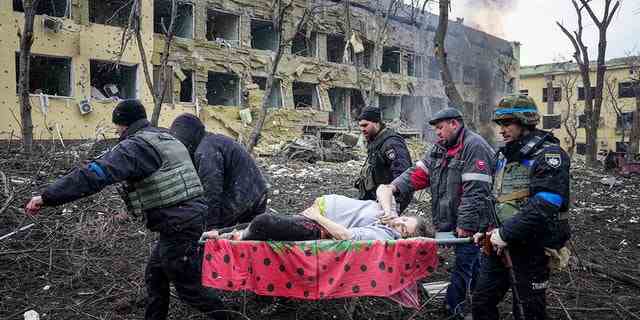 Ukrainische Rettungskräfte und Freiwillige tragen eine verletzte schwangere Frau aus dem durch Beschuss beschädigten Entbindungsheim in Mariupol, Ukraine.  Sie und ihr Baby starben später. 