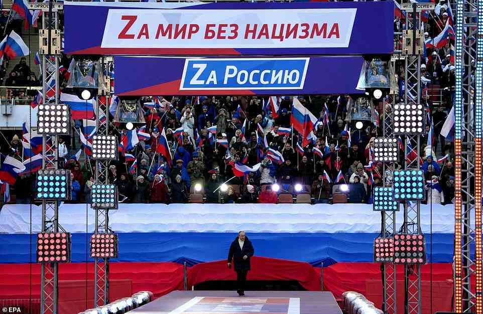 Two banners reading 'For a world without Nazism' and 'For Russia' - each with the letter 'Z' picked out in bold - are seen above the stage as Vladimir Putin arrives to speak to the crowd